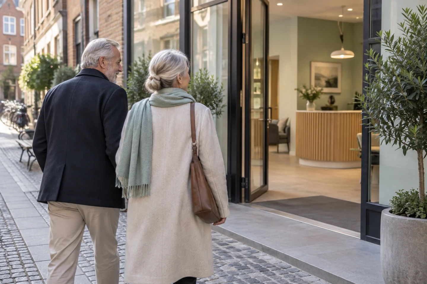An older couple approaching the welcoming step-free entrance of a European hearing centre.